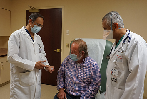 Gunjan Shukla, MD, Clinical Director of Cardiac Electrophysiology (left) and Sunandan Pandya, MD, Medical Director of Echocardiography, show Thomas Donnelly the Watchman device.